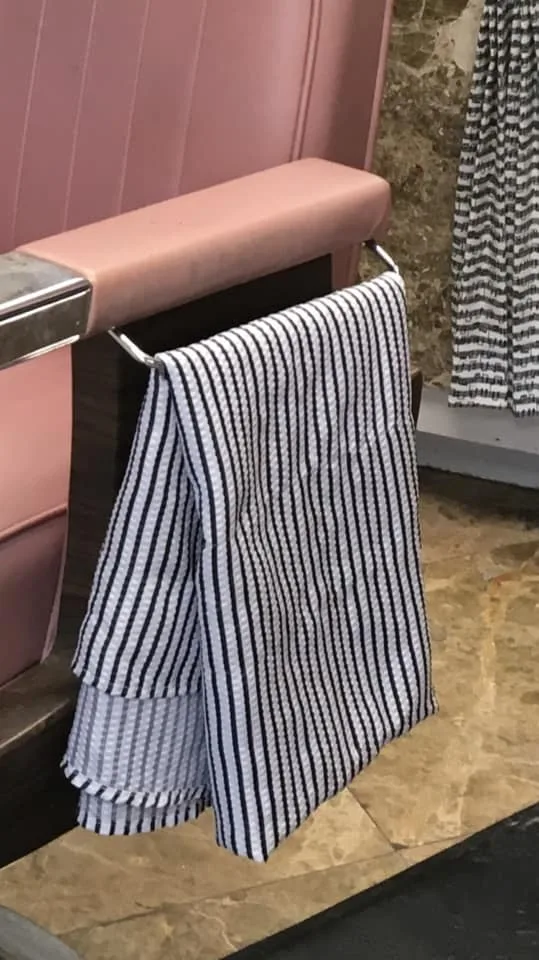 Striped barber cape hanging on a chair